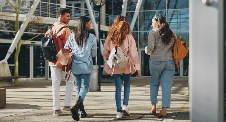 Rear angle photo of a group of students walking toward a campus building